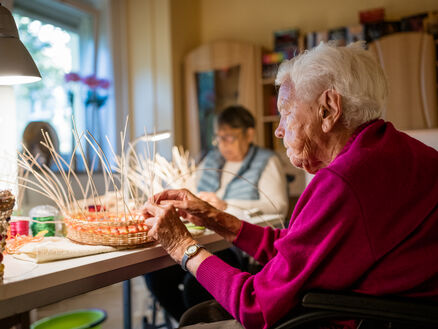 Ältere Frau flechtet Korb